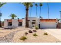 Charming white home with desert landscaping, wrought iron gate and numerous palm trees at 5211 E Winchcomb Dr, Scottsdale, AZ 85254