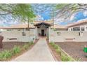 Charming front entrance with a covered walkway, secure fencing, and mature trees at 5540 E Mercer Ln, Scottsdale, AZ 85254