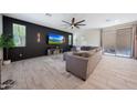 Modern living room with plush sectional sofa, large windows, dark accent wall and tiled floor at 5805 W Warner St, Phoenix, AZ 85043