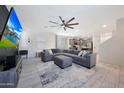 Spacious living room featuring a plush sectional sofa, ceiling fan, tile flooring and modern decor at 5805 W Warner St, Phoenix, AZ 85043