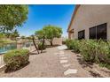 Lush backyard featuring a lakeside view, stone pathway, mature trees, and low maintenance landscaping at 786 S Catalina St, Gilbert, AZ 85233