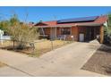 Ranch-style home with a red roof, solar panels, a covered parking area, and a chain link fence at 1116 E Almeria Rd, Phoenix, AZ 85006