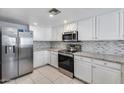 Well-lit kitchen featuring stainless steel appliances, white cabinetry, mosaic tile backsplash, and granite countertops at 11217 E Laurel Ln, Scottsdale, AZ 85259