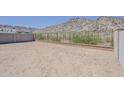 Empty desert backyard surrounded by concrete and wrought iron fence with view of the mountain at 21276 W Mariposa St, Buckeye, AZ 85396