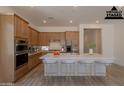 Bright, staged kitchen boasts a large island with bar seating, stainless steel appliances, and warm wood cabinets at 21427 W Meadowbrook Ave, Buckeye, AZ 85396