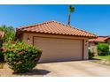 Attractive garage with a tile roof and a well-maintained front yard with lush greenery at 5216 E Half Moon Dr, Phoenix, AZ 85044