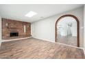 Spacious living room with brick fireplace, wood floors, and a unique archway at 6223 W Earll Dr, Phoenix, AZ 85033