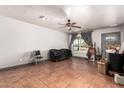 Living room with tile flooring, ceiling fan, window, and door leading to the outside at 6335 W Osborn Rd, Phoenix, AZ 85033