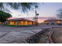 Exterior view of the property featuring desert landscaping, a red tiled roof, and large arched windows at dusk at 8043 E Laurel St, Mesa, AZ 85207