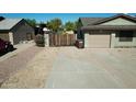Spacious driveway leading to a well-maintained home with a garage and secure wooden gate at 10910 N 72Nd Dr, Peoria, AZ 85345