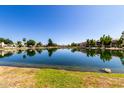 Serene lake view with reflections of waterfront homes and lush trees under a clear blue sky at 11026 N 28Th Dr # 81, Phoenix, AZ 85029