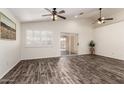 Bright open living room with a sliding glass door, ceiling fan, and wood-look floors at 16118 W Morning Glory St, Goodyear, AZ 85338