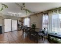 Open dining area with large windows, decorative curtains, tile floors, and hanging vine accents at 25519 W Crown King Rd, Buckeye, AZ 85326