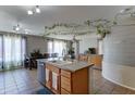 Bright kitchen with center island, tile flooring, hanging vine accents, and ample dining space at 25519 W Crown King Rd, Buckeye, AZ 85326