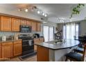 Well-lit kitchen featuring wood cabinetry, a kitchen island with seating, and modern appliances at 25519 W Crown King Rd, Buckeye, AZ 85326