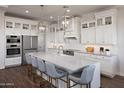A bright white kitchen features a large island with seating, pendant lighting and modern stainless steel appliances at 490 E Aurora Dr, San Tan Valley, AZ 85140