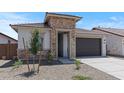 View of a one-story home with a stone facade, neutral paint, and a spacious two-car garage at 7421 S 76Th Ln, Laveen, AZ 85339
