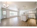 Bright kitchen and dining area featuring modern white cabinets, island, wood floors and ample natural light at 8303 E Monterey Ave, Mesa, AZ 85209