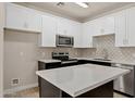 Modern kitchen featuring white cabinets, gray backsplash, stainless steel appliances, and a center island at 1718 W Colter St # 142, Phoenix, AZ 85015