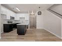 Open kitchen/living area featuring modern white cabinets, black appliances, center island, and staircase to the second level at 1718 W Colter St # 142, Phoenix, AZ 85015