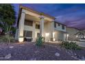 Stately two-story home with manicured landscaping, illuminated by landscape lighting at 20139 N Bustos Way, Maricopa, AZ 85138