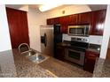 Well-lit kitchen features stainless steel appliances, granite countertops, and warm wood cabinetry at 2025 E Campbell Ave # 120, Phoenix, AZ 85016