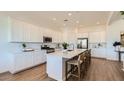 Bright kitchen featuring an island with seating, stainless steel appliances, and white cabinetry at 23244 W Tamarisk Ave, Buckeye, AZ 85326