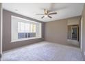 Bright bedroom featuring a large window seat, neutral carpeting, ceiling fan and a large mirror at 3823 W Rose Ln, Phoenix, AZ 85019