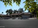 Street view of single-story home featuring mature shade trees, tile roof, and two car garage at 1044 N Abner --, Mesa, AZ 85205