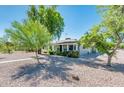 Charming single story home features a rock yard, mature trees, and a covered front porch at 2221 W Mitchell Dr, Phoenix, AZ 85015