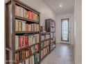 Hallway featuring built-in bookshelves with tile floor leading to a frosted-glass front door at 32729 N Mach Ln, San Tan Valley, AZ 85143