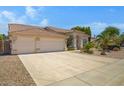 Exterior showcasing a wide driveway, two-car garage, desert landscaping, and a charming arched entryway at 592 W Harvard Ave, Gilbert, AZ 85233
