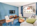 Cozy living room features a large window, blue accent wall, and modern furniture at 6945 E Osborn Rd # B, Scottsdale, AZ 85251