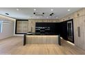 Modern kitchen with stainless steel appliances, black countertops and an island with a built in sink at 8038 E Clarendon Ave, Scottsdale, AZ 85251