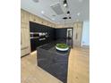 Modern kitchen with stainless steel appliances, black countertops and an island with a built in sink at 8038 E Clarendon Ave, Scottsdale, AZ 85251