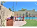 Outdoor kitchen with built-in grill and a view of the backyard swimming pool at 1131 N Cherry --, Mesa, AZ 85201