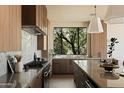 Sleek kitchen with wood cabinets, stainless steel appliances, marble counters, and a bright window overlooking lush greenery at 12887 N 135 St, Scottsdale, AZ 85259