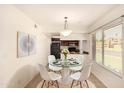 Dining area with glass table, white chairs, modern chandelier and view to the kitchen at 1439 N 53Rd Ave, Phoenix, AZ 85043