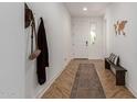 Bright entryway featuring herringbone floors, a long rug, wooden bench, and coat rack at 22853 E Calle Luna --, Queen Creek, AZ 85142