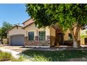 Charming home featuring a stone turret, wrought iron door, manicured lawn, and shade tree at 3229 E Mountain Village Cir, Phoenix, AZ 85042