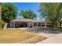 Traditional-style home with a carport and spacious driveway, surrounded by mature landscaping at 4238 E Mitchell Dr, Phoenix, AZ 85018