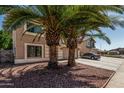 View of a two story home with desert landscaping, palm trees, and an attached two-car garage at 8939 W Villa Rita Dr, Peoria, AZ 85382