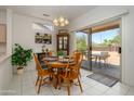 Bright dining area with a round wooden table, complemented by tile flooring and sliding glass doors to the patio at 16354 W Labyrinth Ln, Surprise, AZ 85374