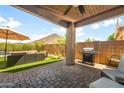 Relaxing covered patio with outdoor furniture, a grill, and views of the pool and meticulously landscaped backyard at 1812 E Parkside E Ln, Phoenix, AZ 85024