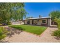 Spacious backyard featuring artificial grass, covered patio, and decorative rock border at 3839 E Friess Dr, Phoenix, AZ 85032