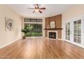 Bright living room featuring fireplace, large window, ceiling fan, and wood flooring at 4135 E Altadena Ave, Phoenix, AZ 85028