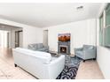Bright living room with tile flooring, featuring a fireplace, stylish sofas, and an open layout to the kitchen at 626 W Tallula Trl, San Tan Valley, AZ 85140