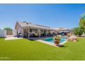 A spacious backyard featuring a swimming pool, covered patio, artificial turf, and mature landscaping at 823 N 81St St, Mesa, AZ 85207