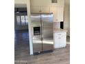 Modern kitchen featuring stainless steel refrigerator, white cabinets, and wood-look tile flooring throughout at 10025 W Shasta W Dr, Sun City, AZ 85351