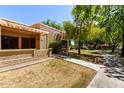 Charming front exterior view with a cozy, covered patio, lush trees, and walkway at 14300 W Bell Rd # 6, Surprise, AZ 85374
